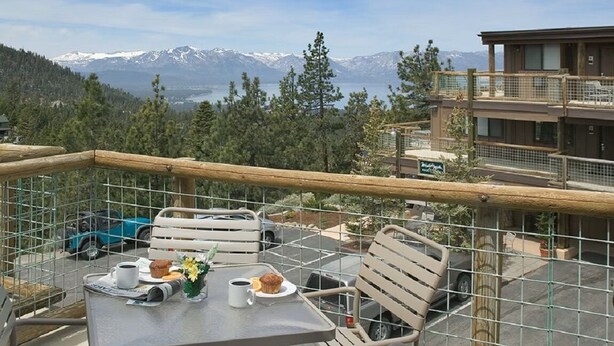 Ein Balkon mit einem Frühstückstisch, mit Blick auf eine gebirgige Landschaft.