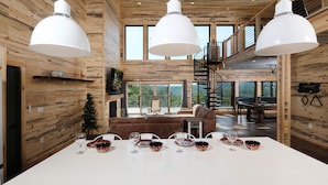 Un interior de madera espacioso con comedor, ventanas amplias y una escalera.