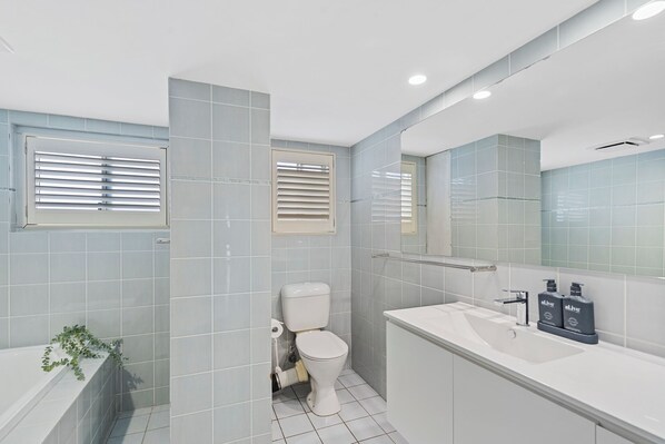Un baño moderno con inodoro, lavamanos y espejo.