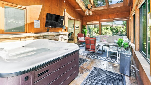 Un jacuzzi en una habitación de madera con un televisor, un sofá y una mesa de comedor.