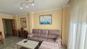Una sala de estar con un sofá, una mesa de centro, un cuadro y un comedor con sillas y una mesa.