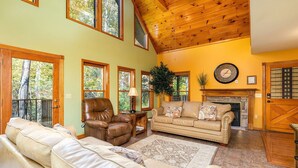 A cozy living room with a leather armchair, a beige sofa, and a fireplace.