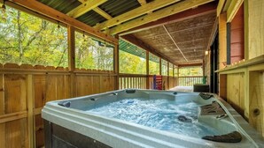 A hot tub in a wooden outdoor area with a wooden deck and a covered section. - Hidden Hollow Lodge - Movie Nights, Game Fun, Fireside Stories & Hot Tub Soaks (Sevierville)