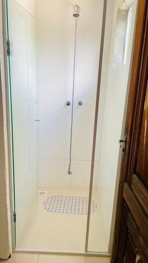 A glass-enclosed shower stall with a metal showerhead, a small window, and a wooden door. - Pousada Don Ruan (Ponta Grossa)