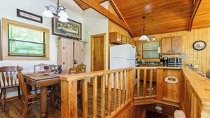 L’intérieur d’un chalet en bois comprend un coin repas, une cuisine et un escalier.