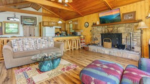 Un intérieur de chalet chaleureux comprenant un salon, une cuisine et une cheminée.
