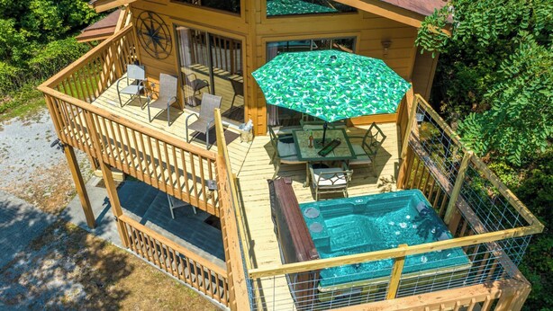 Une terrasse en bois avec des meubles d’extérieur, une piscine et un espace salon abrité.