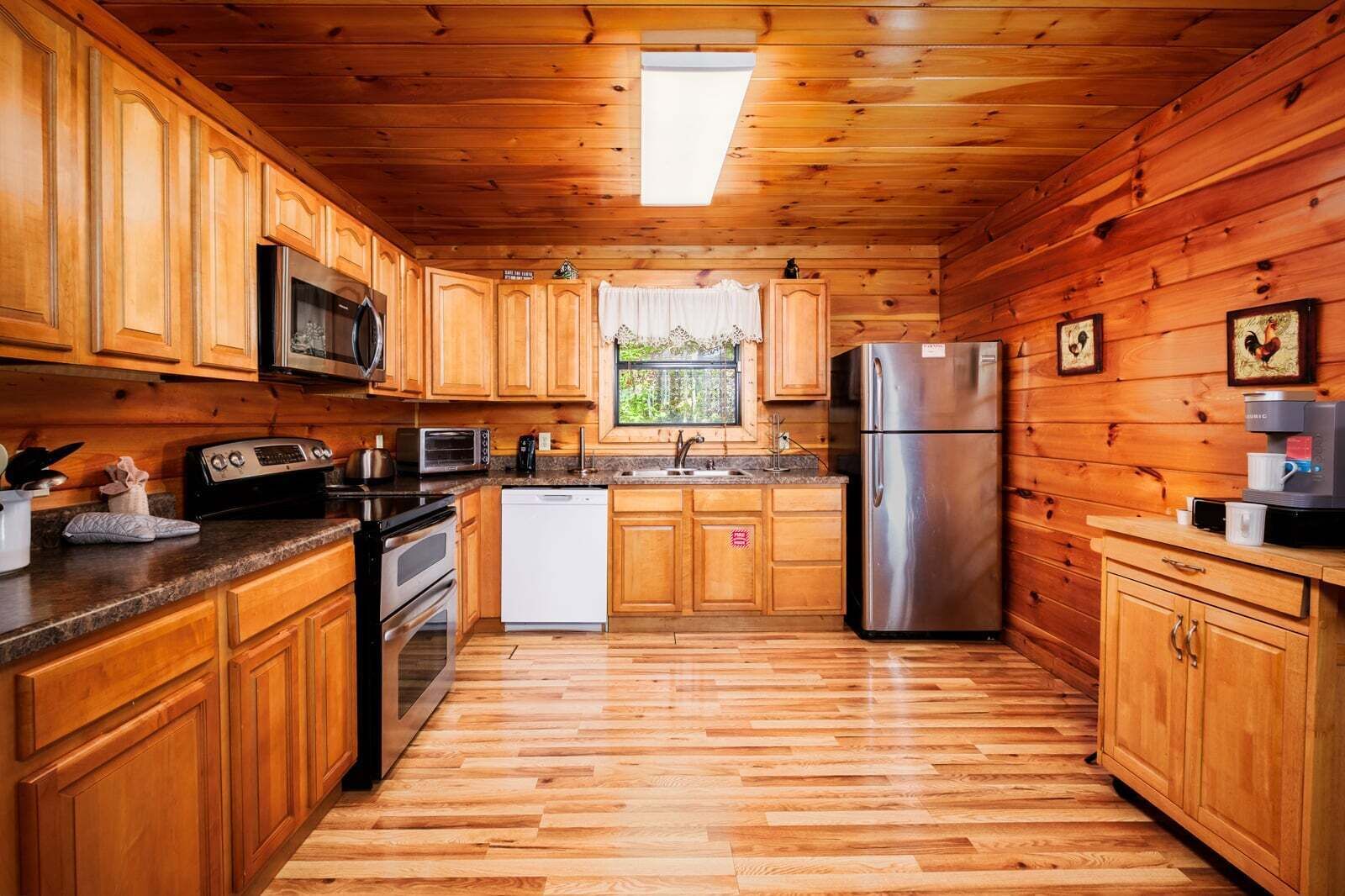 Una cocina tipo cabaña de madera con microondas, estufa, refrigerador y cafetera.