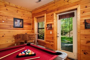 A wooden cabin with a pool table, a door leading outside, and a framed picture on the wall. - Gatlinburg Mountain Heaven Retreat - Hot Tub, Game Room & Fire Pit (Gatlinburg)
