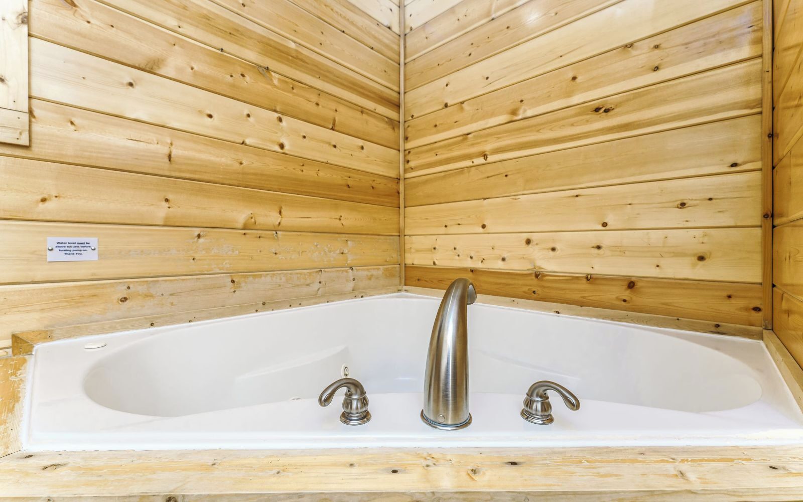 Una cabaña de madera con una bañera blanca y dos grifos.