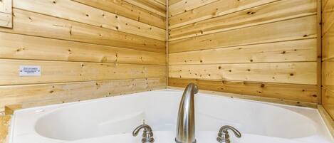 Una cabaña de madera con una bañera blanca y dos grifos.
