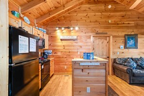 Une cuisine compacte avec des murs en bois, un réfrigérateur, une cuisinière et une machine à café.