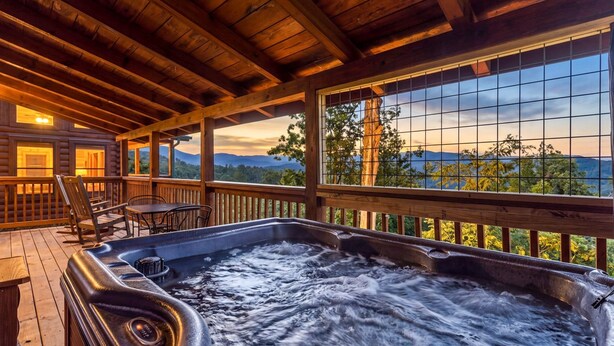 Un bain à remous sur une terrasse en bois, avec vue sur les montagnes.