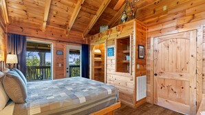Une chambre dans une cabane en bois, avec un lit, une commode, une porte et une fenêtre.