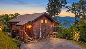 Une cabane en bois dotée d’une véranda, d’un petit abri attenant et offrant une vue sur le paysage environnant.
