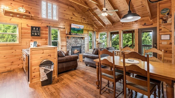 L’intérieur d’une cabane en rondins, avec une cheminée, une table à manger en bois et un canapé.