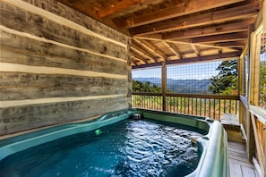 Un bain à remous dans un chalet rustique, avec un intérieur en bois et une vue sur les montagnes.