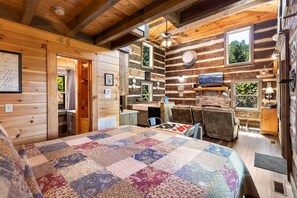 L’intérieur d’une cabane en rondins comprend un grand lit, une table à manger et un coin cuisine.