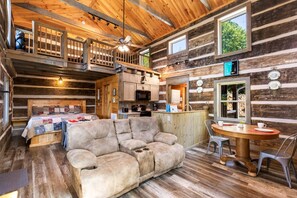 A log cabin interior with a sofa, dining table, and kitchen area. - Sheriff's Cabin - Mountain views from your hot tub! (Gatlinburg)
