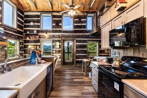 L’intérieur d’une cabane en rondins comprend une cuisine, un coin repas et un escalier menant à un étage supérieur.