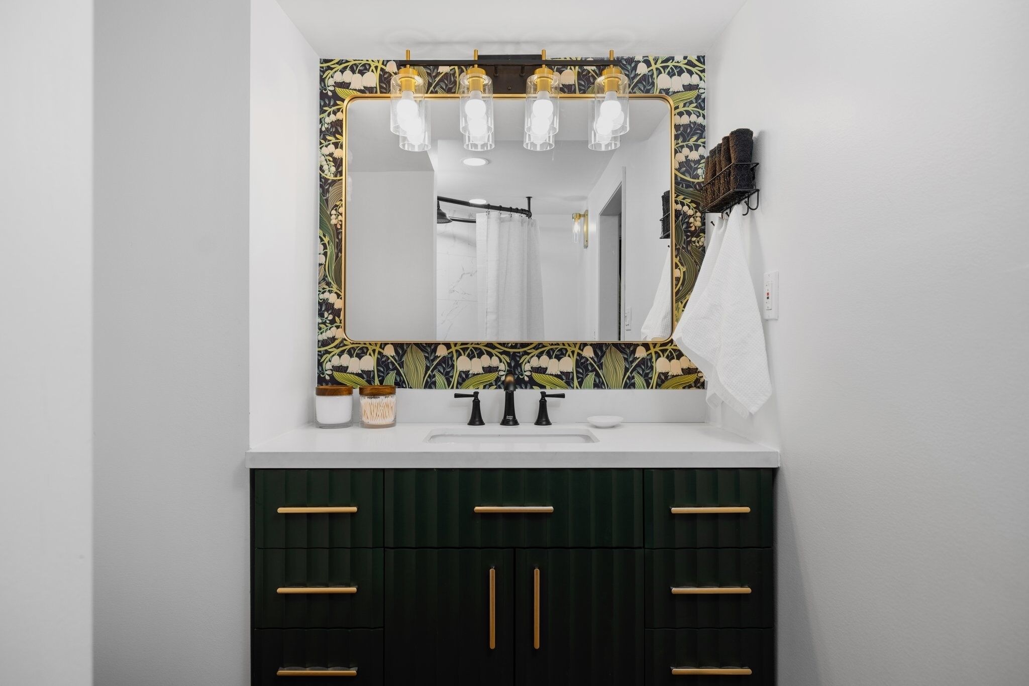 A bathroom with a large mirror, a sink, and dark green cabinets.