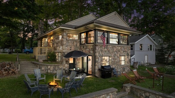 Una casa de piedra con un porche cubierto, mobiliario exterior y una chimenea.