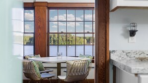 Un área de comedor con una mesa y sillas, una ventana con vista a un lago y una encimera de cocina.