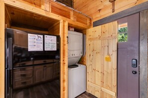 Eine kleine Küche mit einem Kühlschrank, einer Waschmaschine und einer verschließbaren Tür.