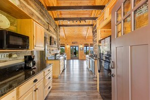 Une cuisine avec des meubles de rangement en bois, un plan de travail noir et un réfrigérateur en acier inoxydable.