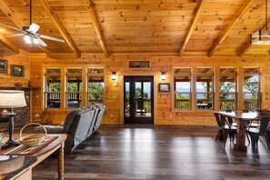 L’intérieur d’une cabane comprend une cheminée, un coin salon, une table à manger et de grandes fenêtres offrant une vue panoramique.