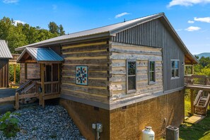 Eine Blockhütte mit Metall-Dach, Holzterrasse und einer Quiltedeko.