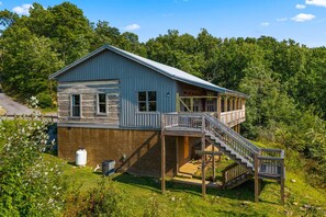 Une cabane en bois à deux étages, dotée d’un balcon et d’un escalier menant à l’étage supérieur.