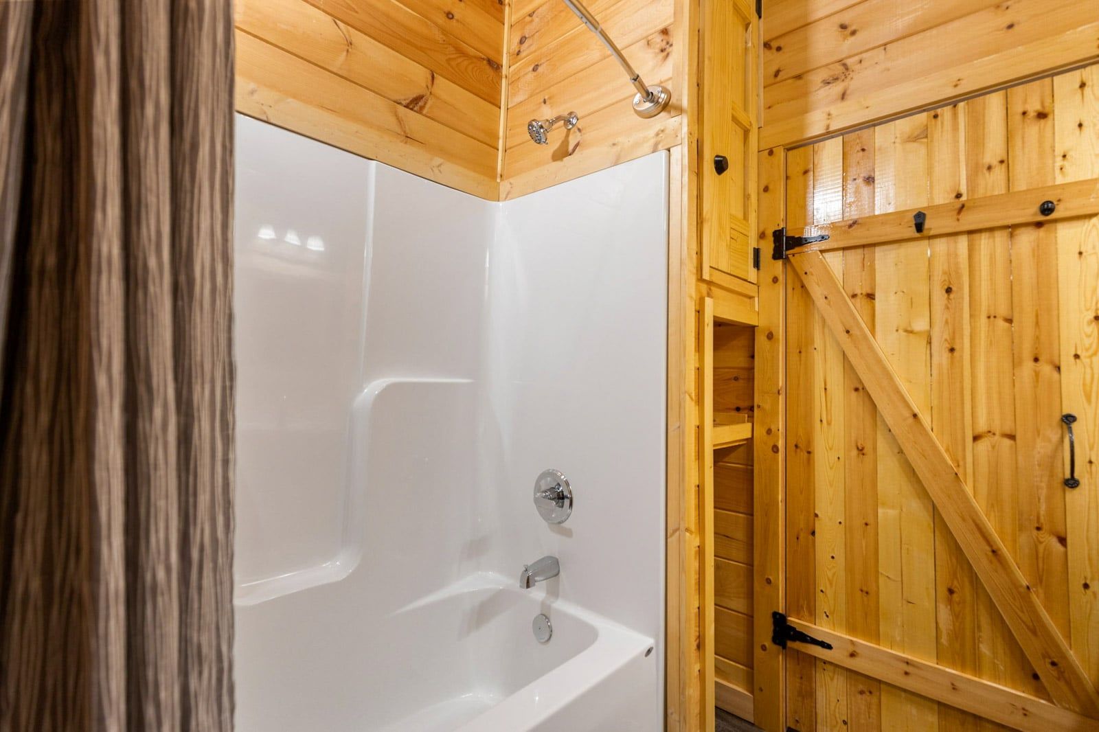Un interior de madera con una bañera blanca y una puerta de madera.