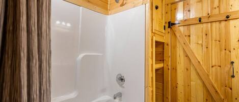 Un interior de madera con una bañera blanca y una puerta de madera.