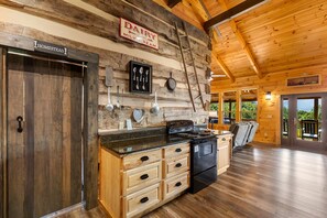 A rustic kitchen with wooden cabinetry, a stove, and a sign for dairy milk and cream. - The Homestead & The Shed - 2 side-by-side cabins! (Gatlinburg)