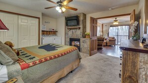 A cozy bedroom with a bed, a fireplace, a TV, and a dining area with a table and chairs. - Grin 'N Bear It - Hot tub, games, and a fireplace! (Sevierville)