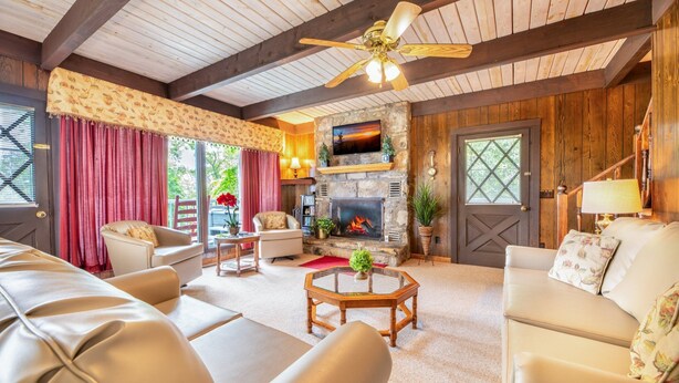 Una sala de estar acogedora con chimenea, sofás de cuero y ventilador de techo.