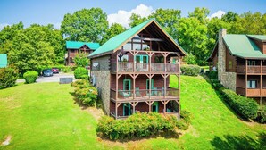 Eine mehrstöckige Blockhütte mit einem grünen Dach, mehreren Balkonen und einem Steinkamin.
