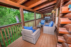 Une terrasse couverte, aménagée avec des meubles en osier et un espace barbecue.