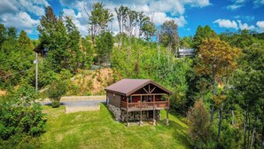 A wooden cabin with a balcony, surrounded by lush greenery and trees.