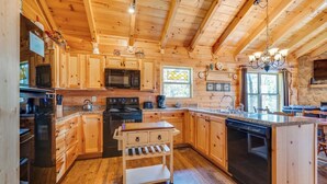 A wooden cabin kitchen with a central island, a microwave, stove, and a dishwasher.