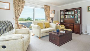A living room with a sofa, armchair, coffee table, and a bookshelf. - The Willows Dinas Cross, Holiday Home Dinas, Sleeps 5, 3 bedrooms,  bathrooms (Newport)