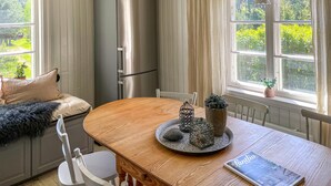 Una cocina acogedora con una mesa de madera, un refrigerador y una ventana que da a zonas verdes.