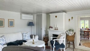 Una sala de estar acogedora con techo blanco, chimenea, sofá, mesa de centro y comedor con sillas y una mesa.