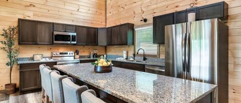 Una cocina moderna con encimeras de granito, electrodomésticos de acero inoxidable y paneles de madera.