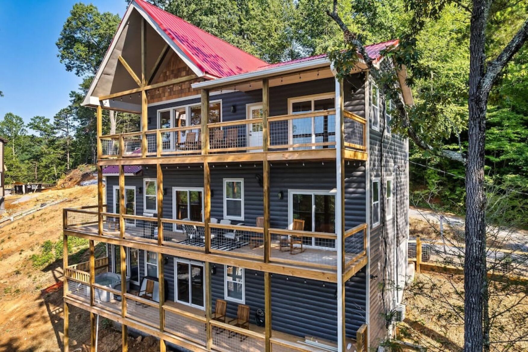 A multi-story log cabin with a red roof, multiple balconies, and a wooden deck.