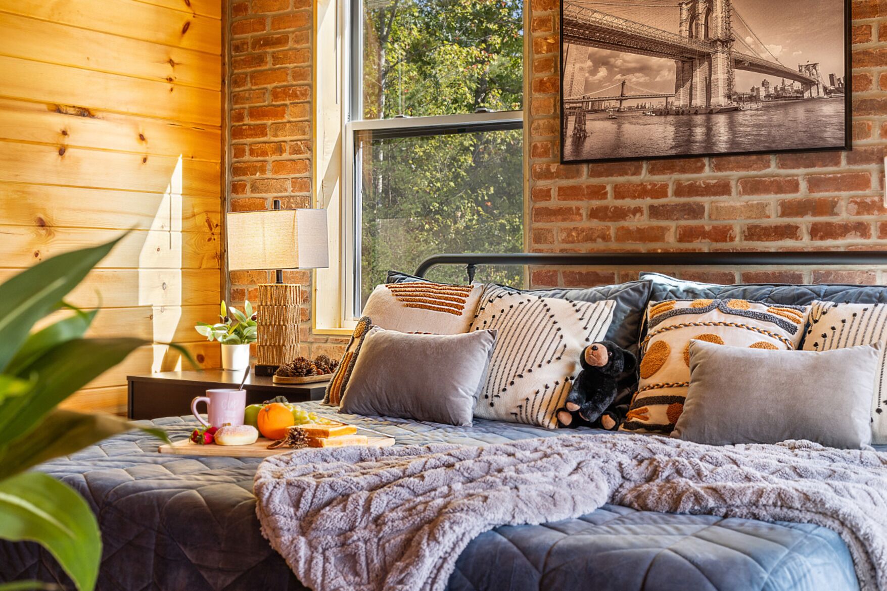 Une chambre confortable avec un grand lit, de nombreux oreillers, une table de chevet avec une lampe et une fenêtre donnant sur un pont.