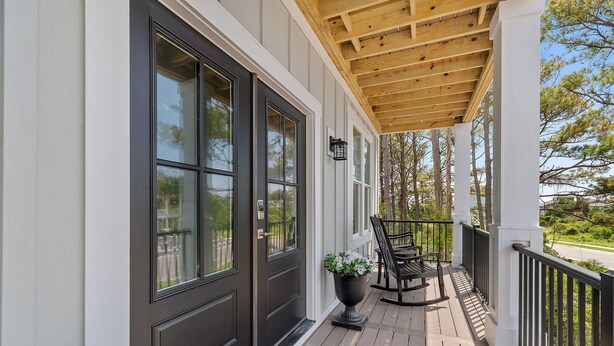 A wooden deck with a black door and windows, a potted plant, and a bench. - NOW AVAILABLE BRAND-NEW! Private beach home with incredible views! (Ocean Isle Beach)
