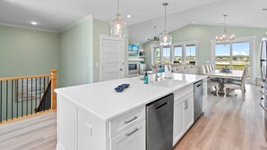 A modern kitchen with white cabinetry, a central island, and pendant lighting. - NOW AVAILABLE BRAND-NEW! Private beach home with incredible views! (Ocean Isle Beach)