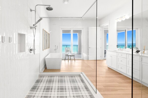 A modern bathroom with a shower, a bathtub, and a large window offering a view of the sea. - Luxurious Beachfront Retreat: Pool, Spa, Chefs Kitchen (Destin)